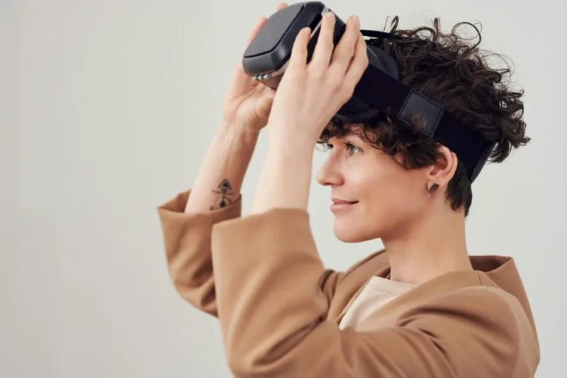 Una profesional con cabello corto experimentando con tecnología de realidad virtual mientras se coloca un visor VR, simbolizando la adopción de tecnologías inmersivas como el metaverso en el entorno empresarial y el futuro del trabajo.